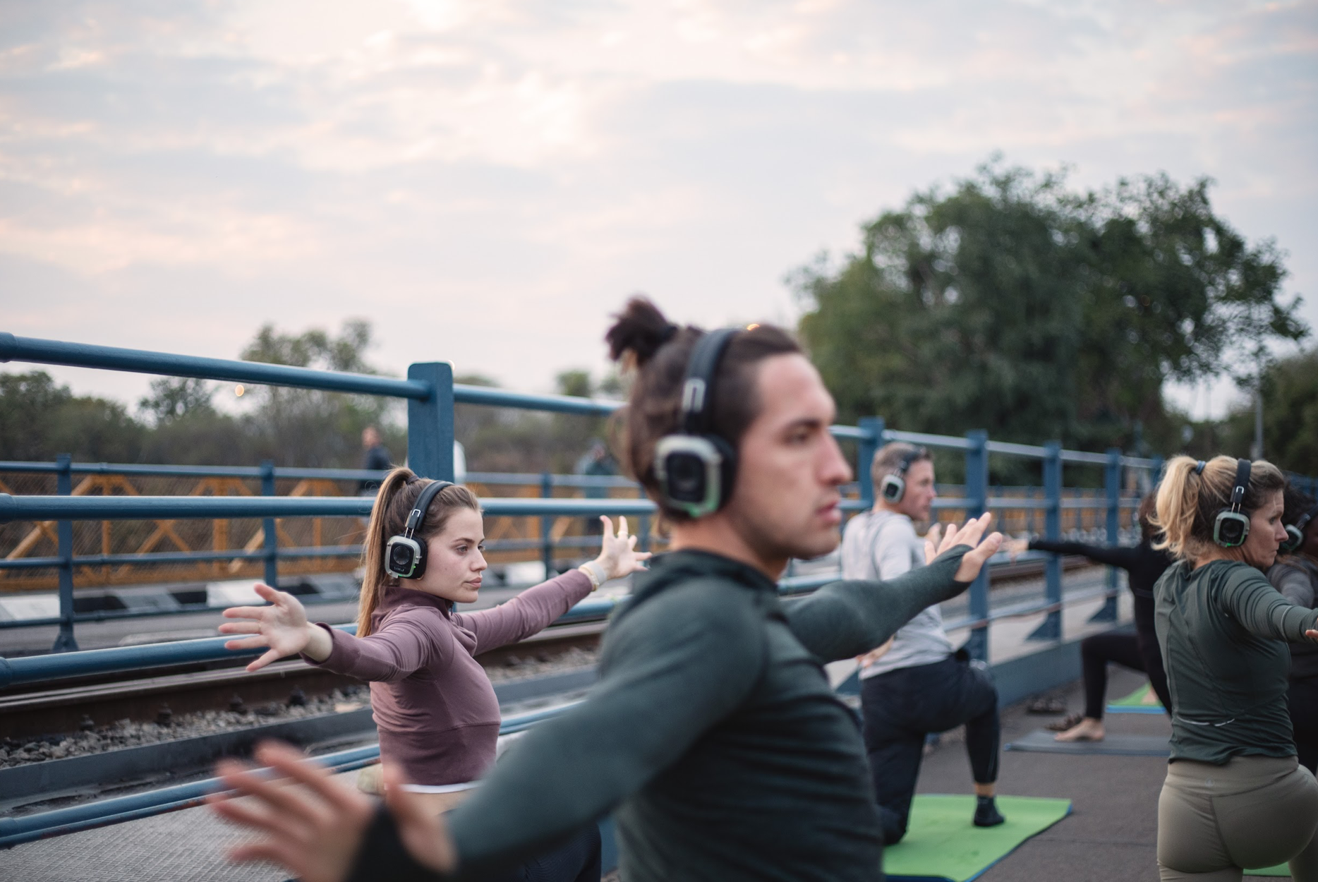 Group standing in silent meditation with headphones on the bridge