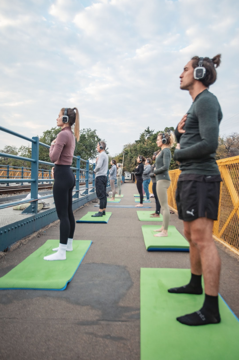 Guests in warrior pose wearing silent-disco headphones on the bridge