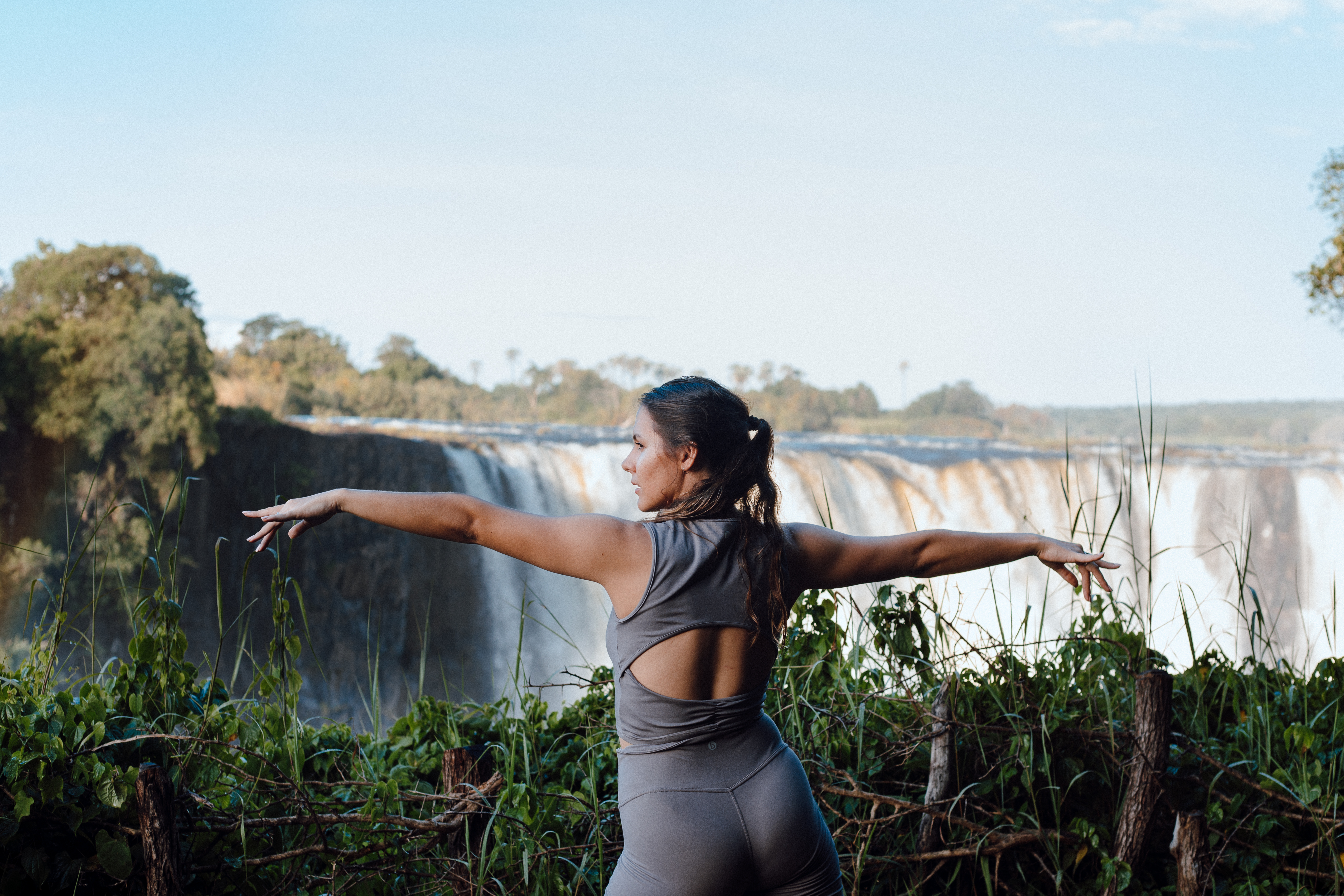 Guest in warrior two pose facing Victoria Falls
