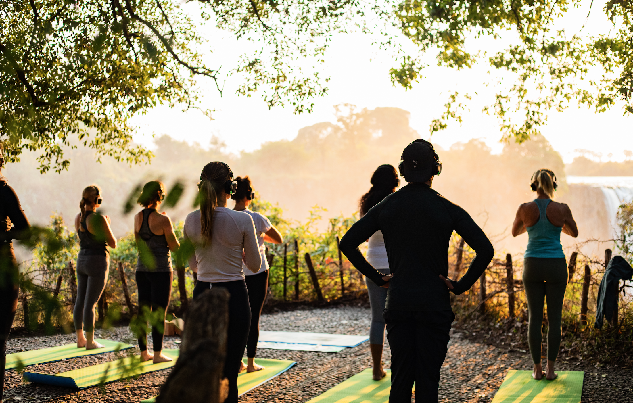 Instructor leading a silent-headphone class overlooking Victoria Falls at sunset