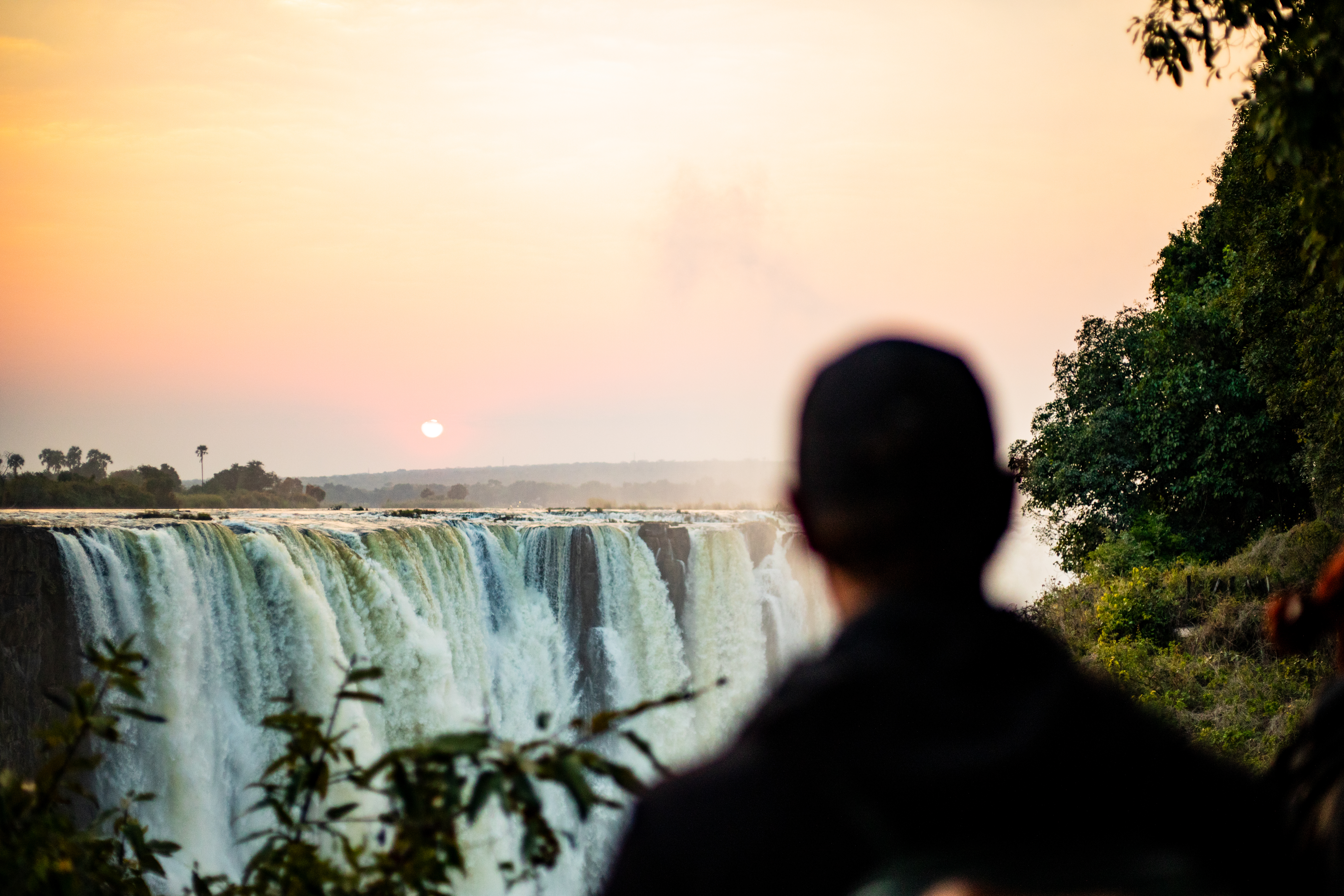 Guest silhouetted against Victoria Falls at sunset