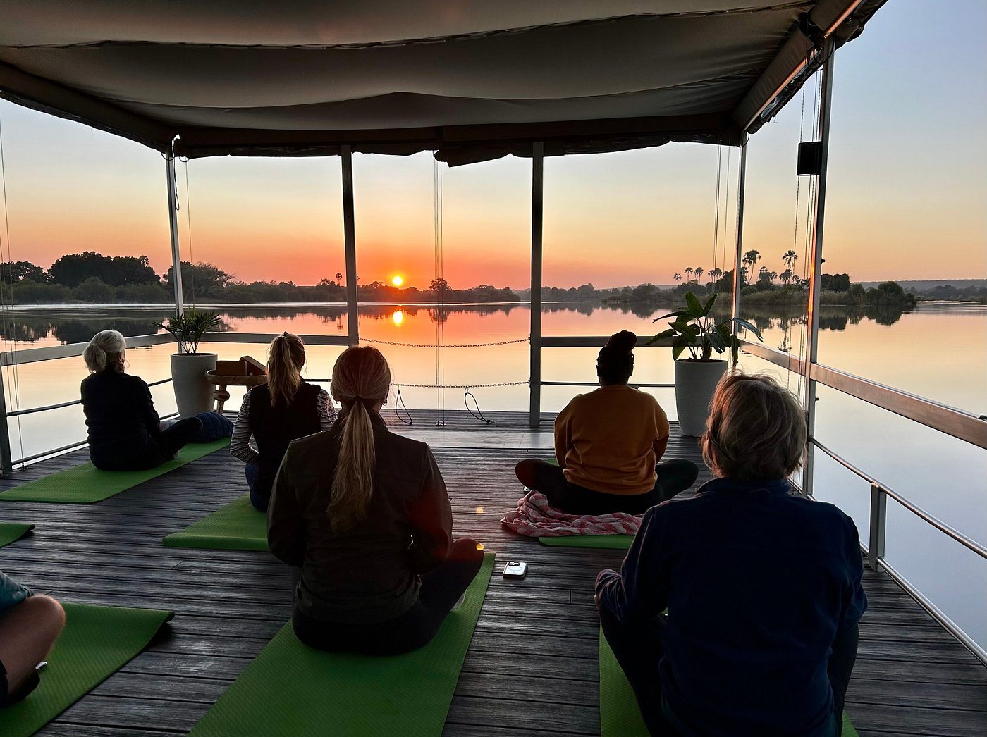 Group meditation silhouetted against a Zambezi sunset